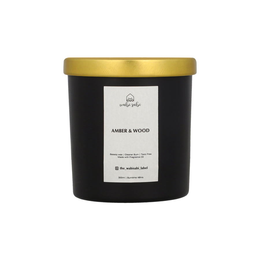 Black candle with gold lid and white label on a white background