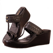 A pair of black leather wedge sandals with studded straps and braided detail, shown on a plain white background.