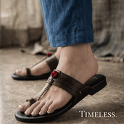 Person wearing a pom pom kolhapori with decorative elements on a textured floor, with 'Timeless' text.