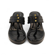 A pair of black platform thong sandals with studded straps and gold-tone hardware, shown from a top-down view on a white background.